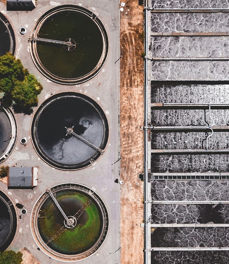 Usine industrielle avec bassin d'eau, illustrant les enjeux de l'optimisation la consommation d'eau industrielle.